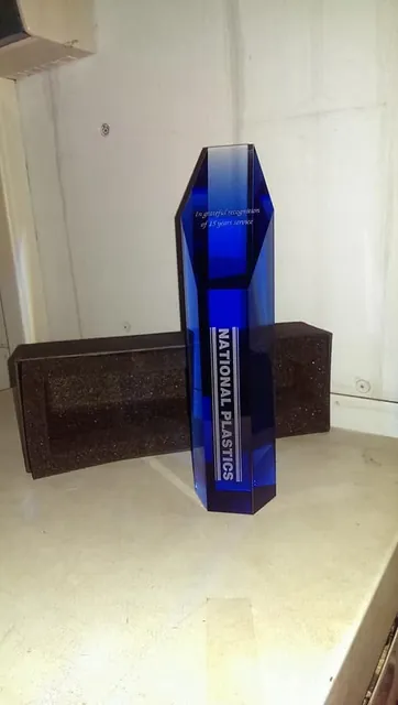 Tall blue crystal column award engraved with a company name and a 25 years service message
