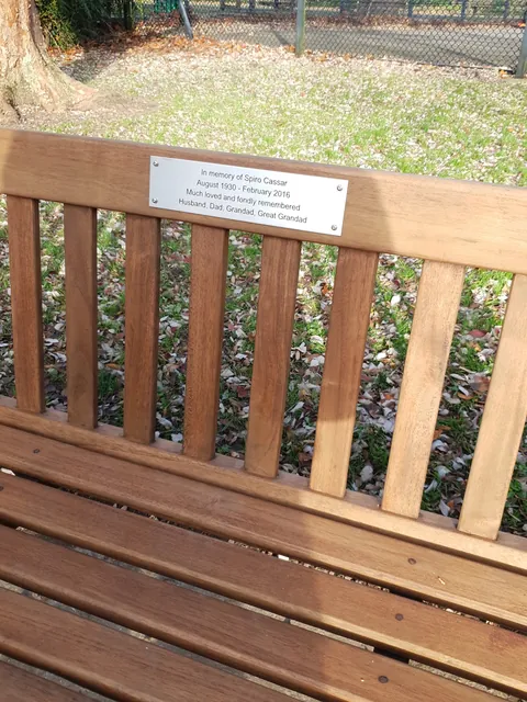 Stainless steel memorial plaque with four lines of text on a new hardwood bench